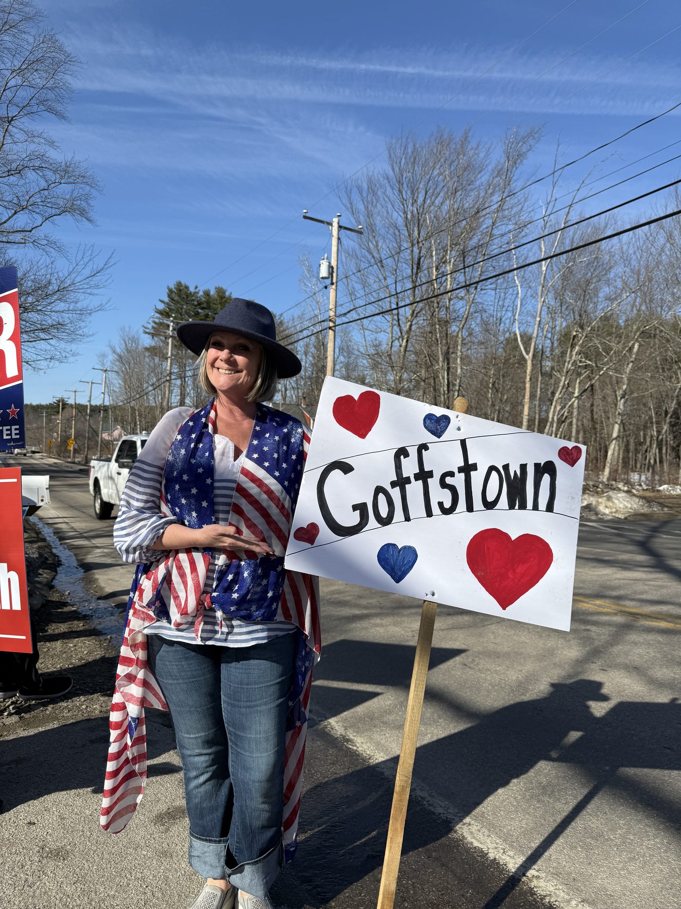 Sherri Reinfurt holding a hand-painted "Goffstown" heart sign at a community sign wave